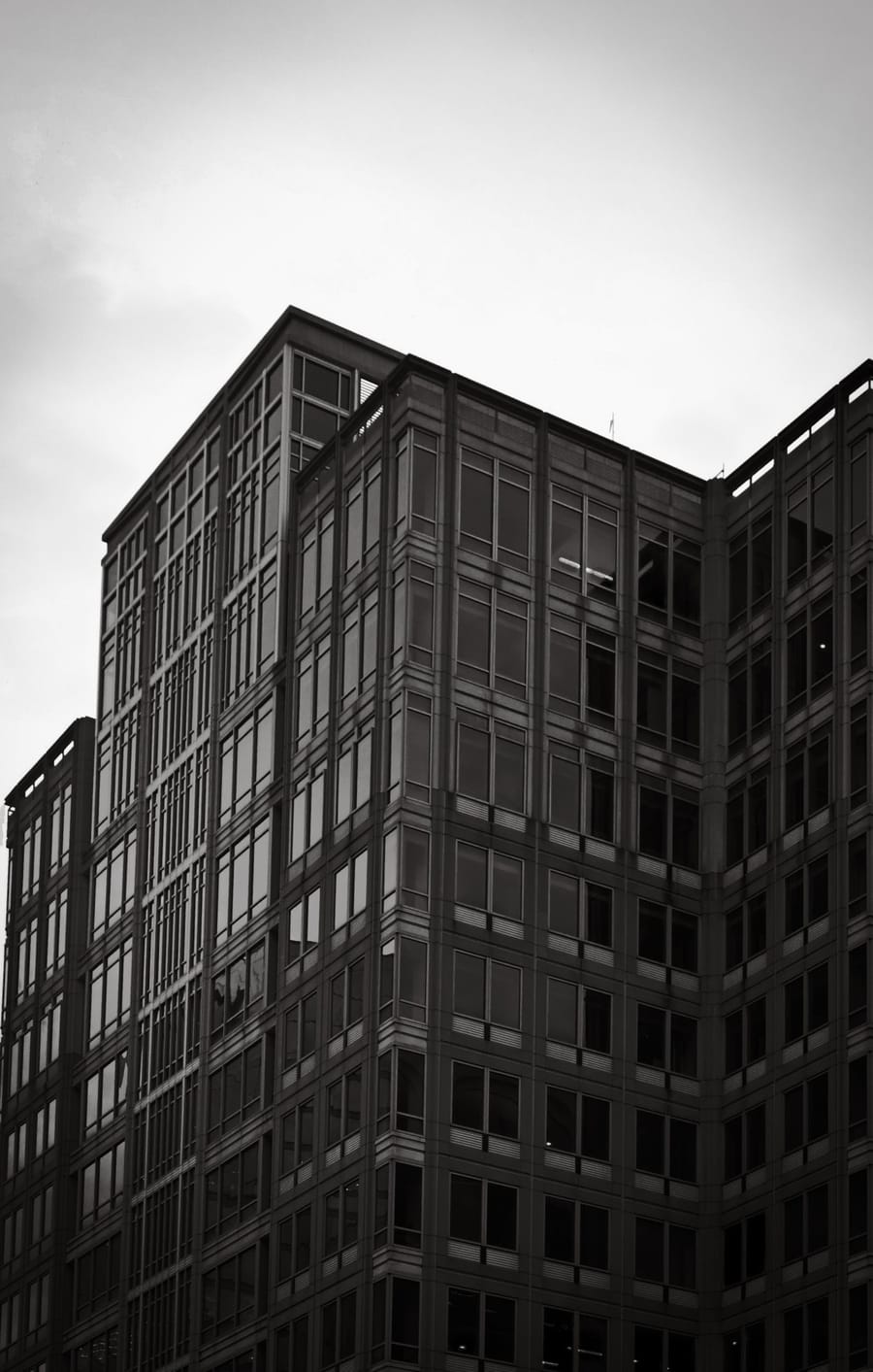 Black and white glass office building rising into a grey sky